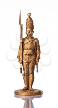 Golden tin soldier on a white background with reflection.