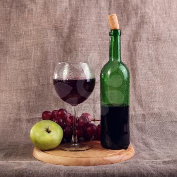Red wine, cheeses and grapes and apple in a still life setup.