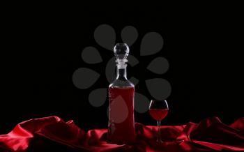 glass and bottle of wine on a dark background silk