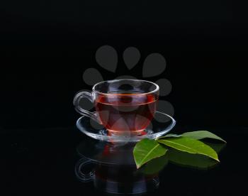 Glass cup of tea on black background.