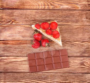Piece of strawberry tart and fresh raw strawberries on wooden table.