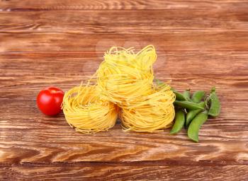 Pasta on the wooden background with tomatoes and peas