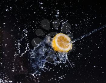 A high-speed shot of a lemon with splashing water, on a black background.
