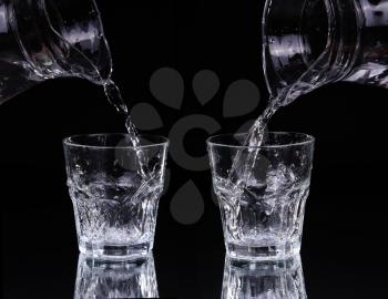 pouring water on a glass on black background