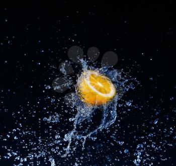 Lemon  into water splash on black background