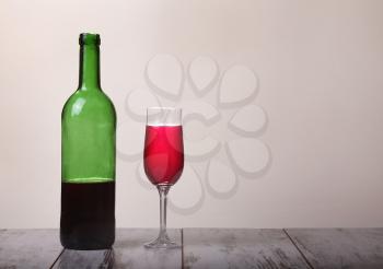Bottle with red wine and glasses on wooden table. Grey background