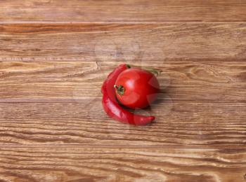 Red peppers and tomato wood grain background.