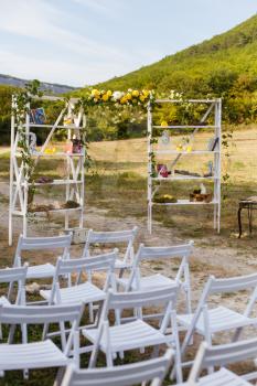 Happy outdoor Wedding Ceremony Scene for a summer mountain wedding. Wedding aisle, decorated wedding alter and flower decorations with mountains in the background. Wedding color pear