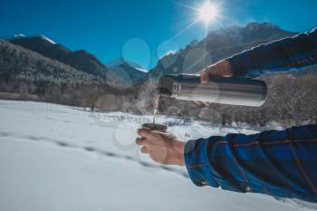 Man holding a thermos in on a snowy mountain