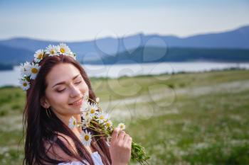 Beautiful woman enjoying daisy field, nice female lying down in meadow of flowers, pretty girl relaxing outdoor, having fun, holding plant, happy young lady and spring green nature, harmony concept