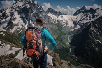 Woman hiking around mountains at spreeng time. Dombai, Karachay-Cherkessia, Russia