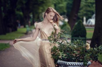 A young red-haired girl in a delicate peach dress is walking along a beautiful old town. St.Petersburg