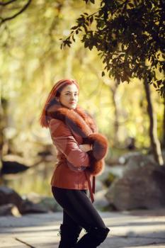 Beautiful red-haired young woman is walking in the autumn park. melancholy mood