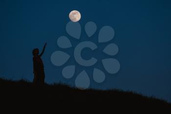 Beautiful silhouette of a young woman against a background of the night sky with a full moon
