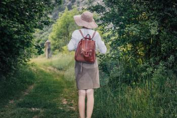 woman traveler with backpack and hat walking in amazing mountains and forest, wanderlust travel concept, space for text, atmospheric moment. earth day