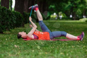 Young beautiful woman meditates on a summer day in the park. Idea and concept of calm in a busy city and a healthy lifestyle, stretching and preparing for a run in the park