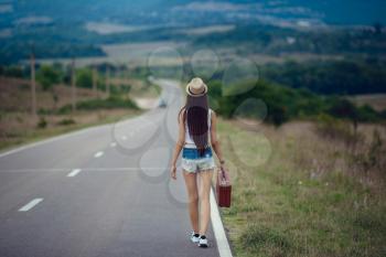 Freedom travel concept. summer weekend. hipster girl wanderlust walking on asphalt road in wild lands. Beautiful young girl with the appearance of southern Asia