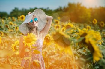 beautiful sweet sexy girl in a blue dress walking on a field of sunflowers , smiling a beautiful smile,cheerful girl,style, lifestyle , ideal for advertising and photo sun shines bright and juicy