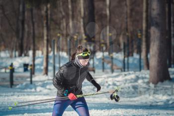 Cross-country skiing woman doing classic nordic cross country skiing in trail tracks in snow covered forest. Training track for skiers in the park of Moscow, Odintsovo