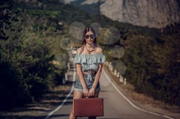 Young beautiful Asian woman in hippy style. travels by hitchhiking. Road in the mountains