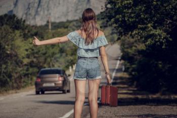 Young beautiful Asian woman in hippy style. travels by hitchhiking. Road in the mountains