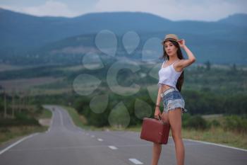 women is hailing a car on a road. Thumbing a ride. Outdoors vacation. Asian