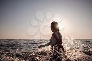 Beautiful emotional Model Girl making splash in the sea and laughing. Beautiful Woman Hot Girl enjoying the Waves of the Ocean. Tropical vacation