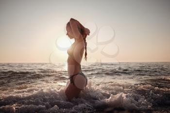 Beautiful emotional Model Girl making splash in the sea and laughing. Beautiful Woman Hot Girl enjoying the Waves of the Ocean. Tropical vacation