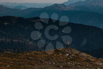 silhouette of Young male hipster in the mountains in autumn. Discovery Travel Destination Concept. Tourist on the high rocks background. Sport and active life concept.