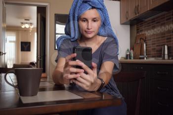 Young Asian woman looking at phone and working at self-isolation at her kitchen. Coronavirus. Quarantine. isolation, social distancing, freelance work from home office.
