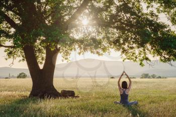 Attractive woman practices yoga in nature in summer. Healthy lifestyle. Fitness and sport. outdoor harmony with nature, calm scene