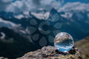 beautiful spherical glass ball with majestic Caucasian mountains, Dombai, Russia. the idea and concept of discovery, travel and trekking, Hiking theme.