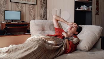 Sick and Flu Woman. Caught Cold. Woman feeling cold with blanket resting on the sofa at home