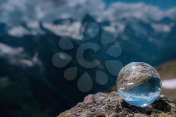 beautiful spherical glass ball with majestic Caucasian mountains, Dombai, Russia. the idea and concept of discovery, travel and trekking, Hiking theme.