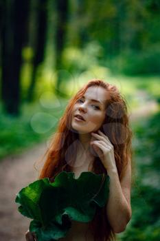 Protection of the environment, rescue of plants and nature. A young ginger woman stand in the green fairy forest. Idea and concept of Arbor day or Mother earth day