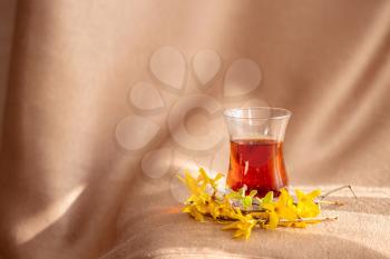 traditional turkish tea cup witk yellow flower on fabric background by the window. warm tinting. idea and concept of tea party, spring, tranquility and silence