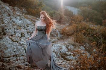 beautiful furious scandinavian warrior ginger woman in grey dress with metal chain mail. Woman is a Viking. Fantasy. Book Cover. beautifully flying dress