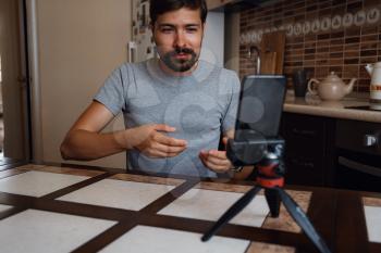 Young man having video call via smartphone in the home office. Virtual house party. confident young guy vlogger influencer shooting social media video blog talk at home