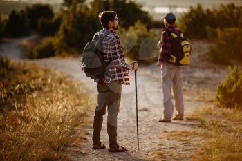 two men hikers enjoy a walk in nature, sunset time in summer. enjoying their adventure. Lifestyle hiking concept vacations outdoor