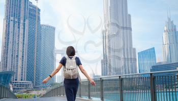 Young beautiful woman enjoying the view of Dubai downtown. Enjoying travel in United Arabian Emirates. view from the back or rear view, the lady walks away from the photo camera