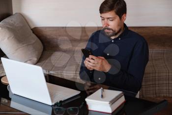 Handsome young man working on laptop. Businessman using phone. Freelance business work from home concept