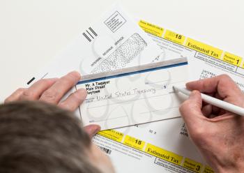 Male caucasian hands writing check to Internal revenue service IRS form 1040-ES for payment of estimated taxes in 2015