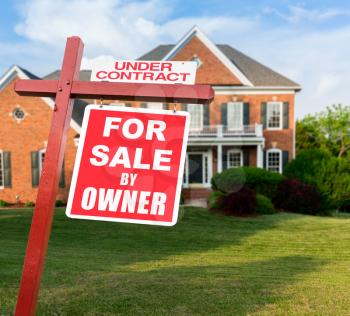 For Sale and Under Contract realtor sign in front of large brick single family house in expansive grass yard for real estate opportunity