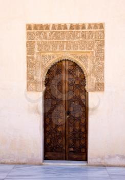 Simple wooden doorway with ornate arch in courtyard of Alhambra palace Granada, Spain