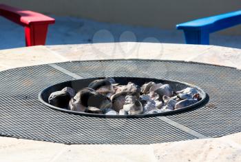 Gas or propane powered firepit with white hot coals and rocks and relaxing chair