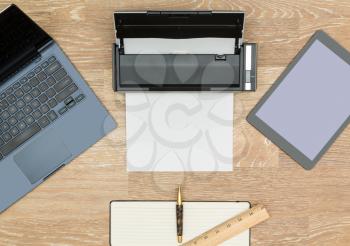 Tidy organized desk top with laptop, tablet, scanner and notebook with pen on an oak wooden table for designer workspace