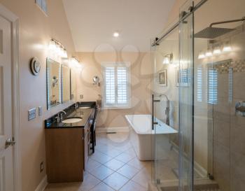 Interior of modern bathroom with standalone tub, walk in double tiled shower and granite vanity bar