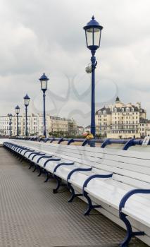 View across and empty deserted row of benches at the end of the pier in Eastbourne looking towards the promenade