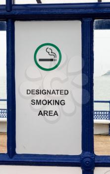 Sign for Designated Smoking Area on pier by seaside in vacation town in England, UK