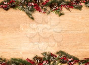 Christmas or Xmas Holiday background on old plank wood with fir branches, red berries, pine cones and snow